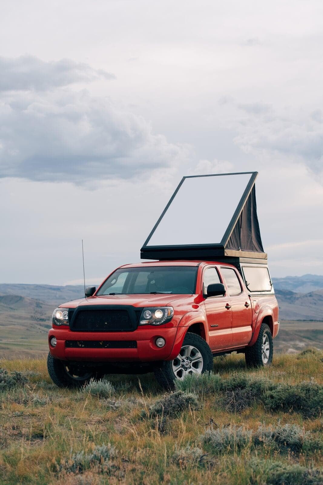 Red truck in field with pop-up camper mounted on bed
